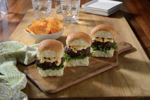 Photo of 3 chipotle burgers sliders on a wood cutting board